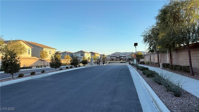 view of street featuring traffic signs, a residential view, curbs, and sidewalks