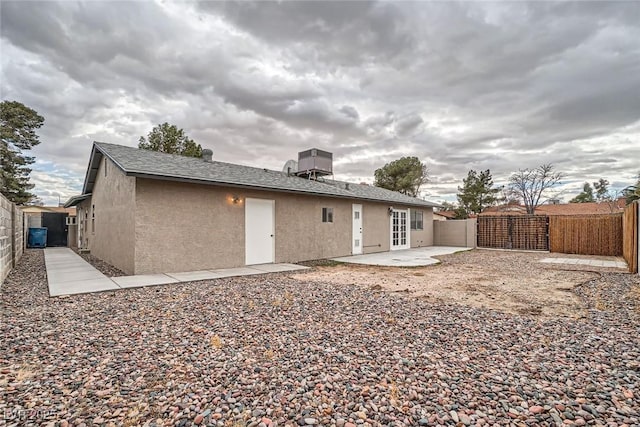 rear view of property with stucco siding, a shingled roof, a gate, a patio area, and a fenced backyard