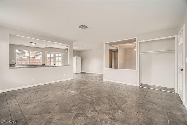 unfurnished living room featuring ceiling fan, visible vents, and baseboards