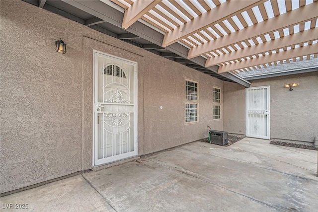 property entrance featuring stucco siding, a pergola, and a patio