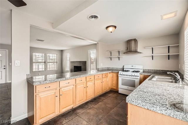 kitchen featuring white range with gas stovetop, visible vents, wall chimney exhaust hood, open shelves, and a sink