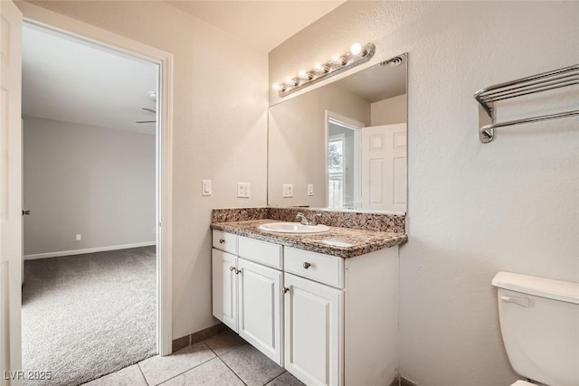 half bathroom featuring toilet, vanity, baseboards, and tile patterned floors