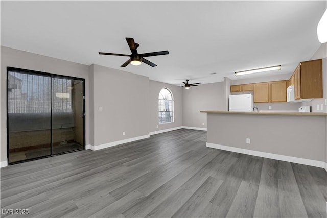 unfurnished living room featuring ceiling fan, baseboards, and dark wood-style flooring