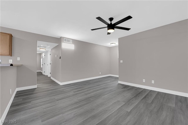 unfurnished room featuring baseboards, ceiling fan, visible vents, and dark wood-type flooring