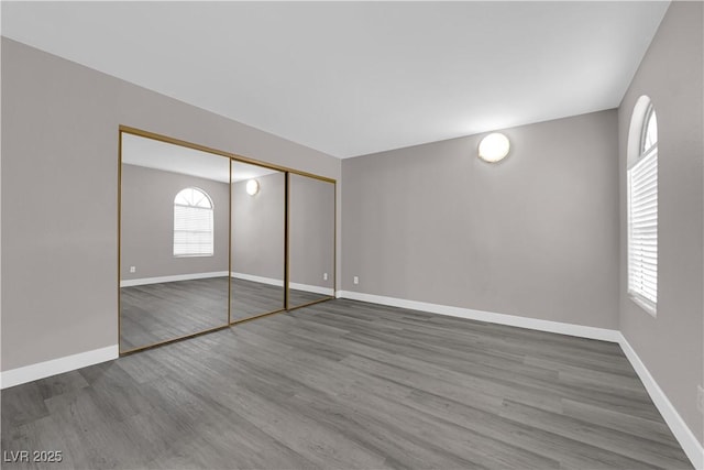 unfurnished bedroom with a closet, baseboards, and wood finished floors