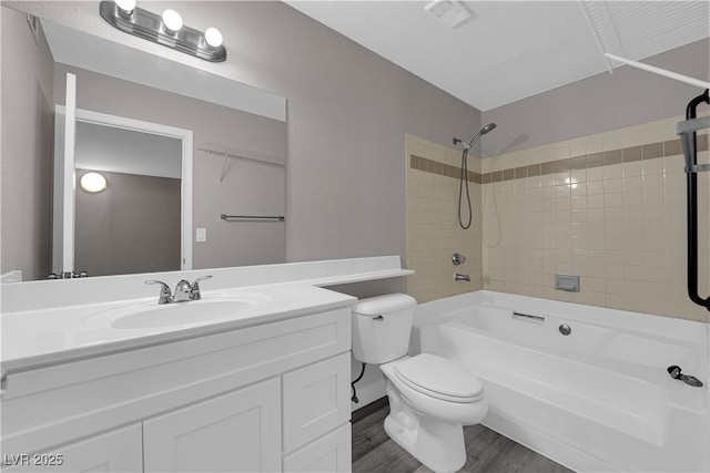 bathroom featuring toilet, vanity, wood finished floors, and shower / bathtub combination