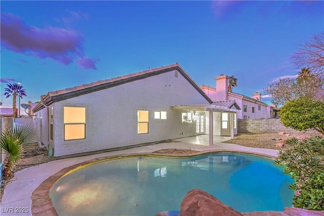 pool at dusk with a patio, a fenced backyard, and a fenced in pool