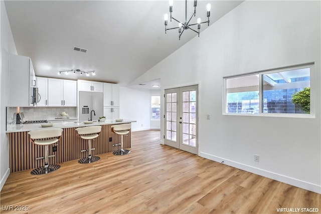 kitchen featuring light wood finished floors, visible vents, light countertops, fridge with ice dispenser, and french doors