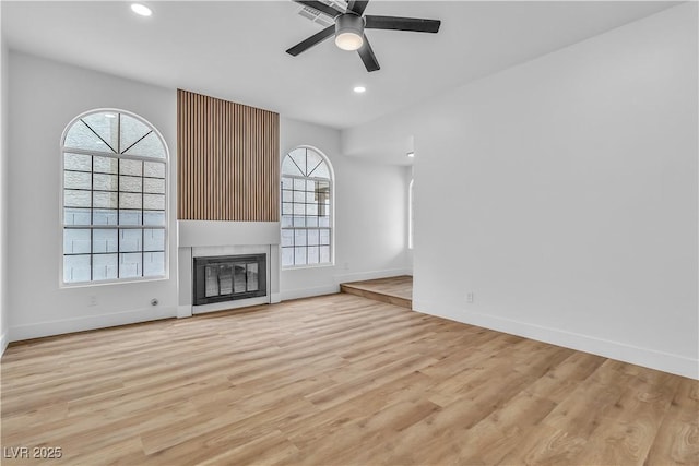 unfurnished living room with light wood-type flooring, a healthy amount of sunlight, and a ceiling fan