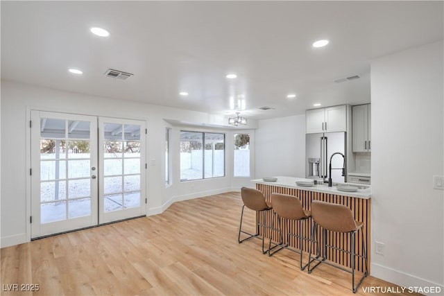 kitchen with visible vents, a breakfast bar, recessed lighting, high quality fridge, and light wood finished floors