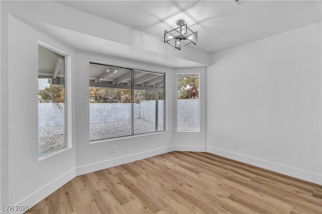 unfurnished dining area with an inviting chandelier, light wood-style flooring, baseboards, and a wealth of natural light