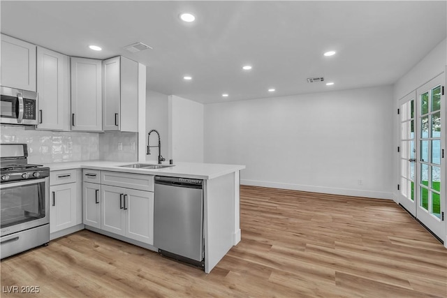 kitchen with decorative backsplash, light wood-style floors, appliances with stainless steel finishes, and a sink