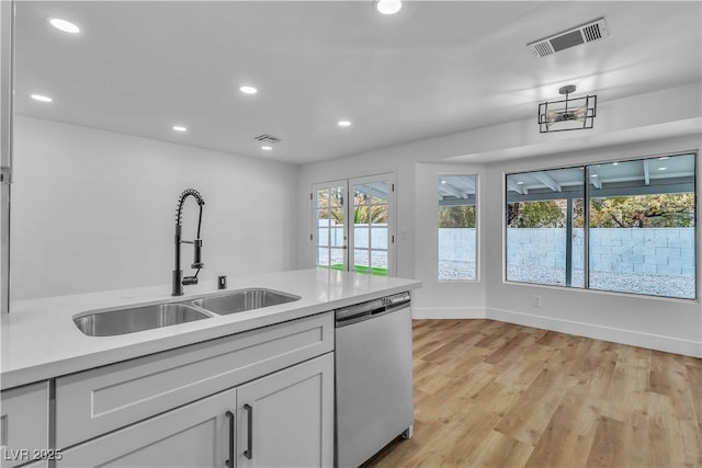 kitchen featuring a sink, visible vents, dishwasher, and light countertops