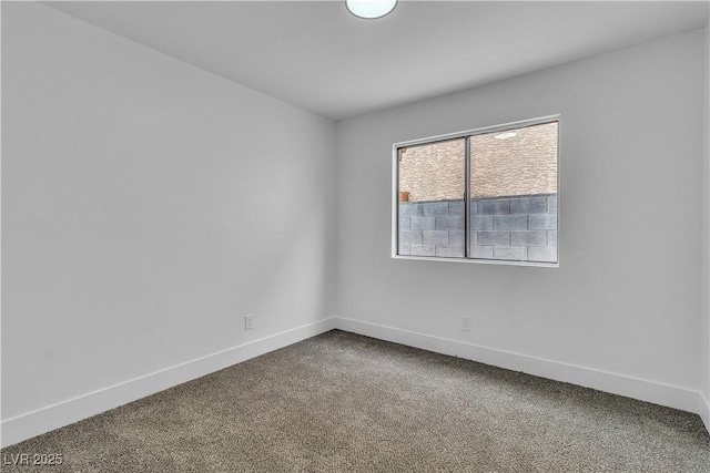 spare room featuring baseboards and dark colored carpet