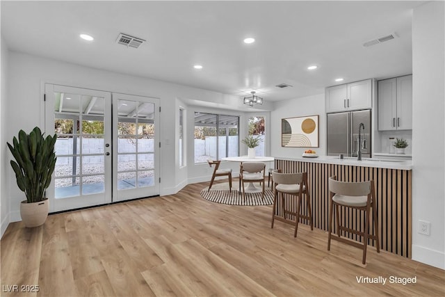 kitchen with visible vents, a kitchen bar, light wood-style floors, and stainless steel refrigerator with ice dispenser