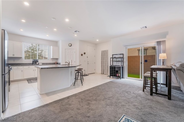 kitchen featuring open floor plan, light carpet, visible vents, and white cabinetry