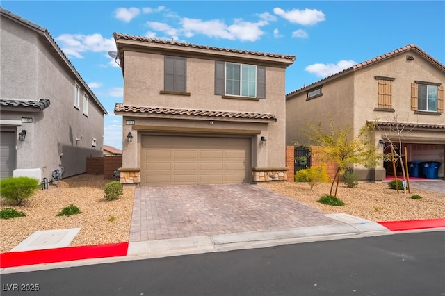 mediterranean / spanish house featuring a garage, decorative driveway, fence, and stucco siding