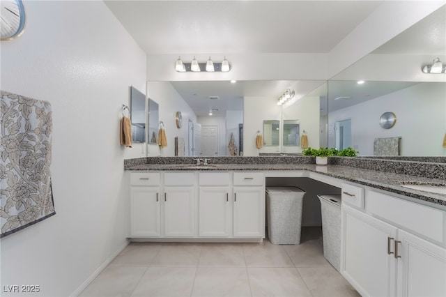 bathroom with tile patterned flooring, two vanities, a sink, and baseboards