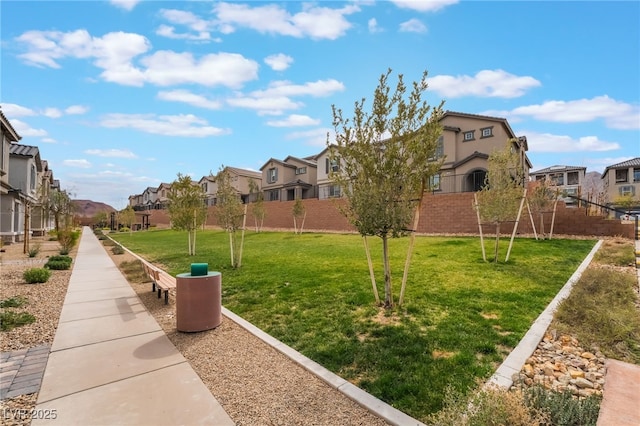 view of community with a residential view, fence, and a lawn