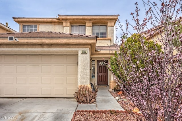 view of front of home with an attached garage, concrete driveway, and stucco siding