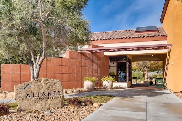 property entrance featuring roof mounted solar panels and fence