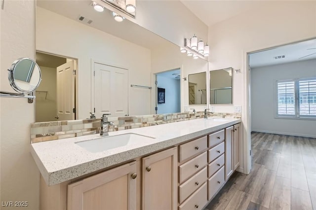 bathroom featuring double vanity, visible vents, a sink, and wood finished floors