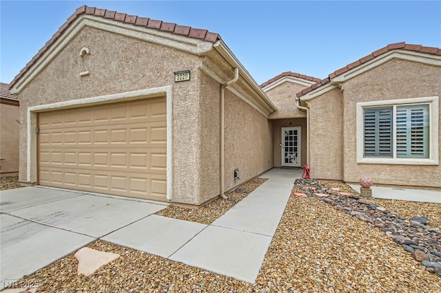 view of front of home featuring a garage, driveway, a tiled roof, and stucco siding