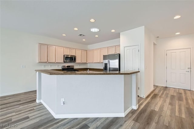 kitchen featuring light wood-type flooring, baseboards, appliances with stainless steel finishes, and light brown cabinetry