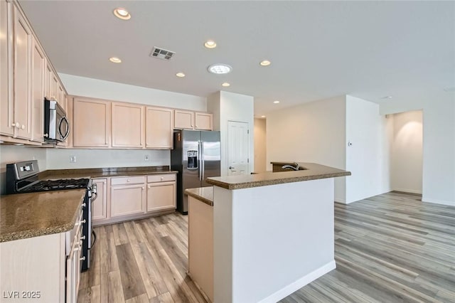 kitchen with appliances with stainless steel finishes, dark countertops, visible vents, and light wood finished floors