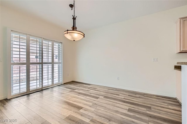 unfurnished dining area featuring light wood finished floors and baseboards