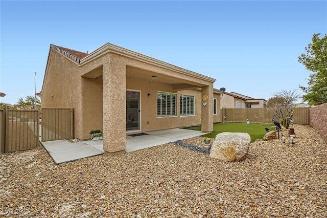 back of house featuring a patio area, a fenced backyard, a gate, and stucco siding