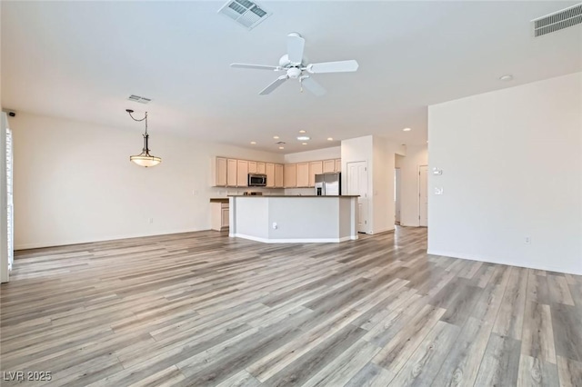 unfurnished living room featuring light wood-type flooring, ceiling fan, and visible vents