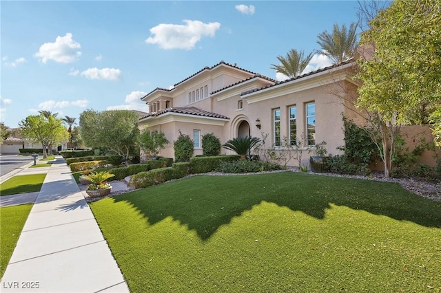 mediterranean / spanish-style house featuring a front yard, a tiled roof, and stucco siding