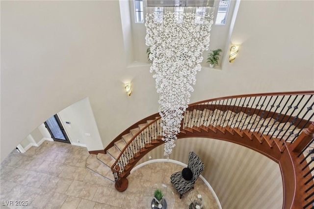 stairway featuring a high ceiling, baseboards, and arched walkways