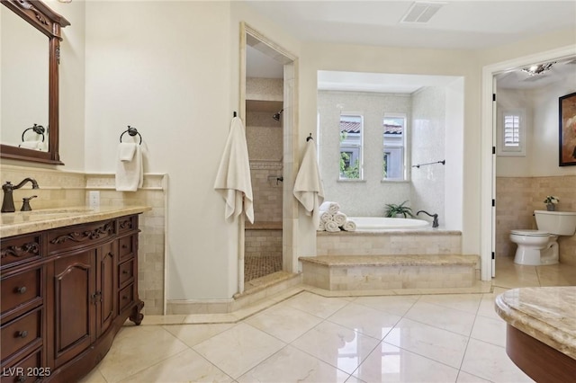 full bath with tile walls, visible vents, a stall shower, vanity, and tile patterned floors