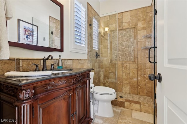 bathroom featuring toilet, a stall shower, tile walls, and vanity