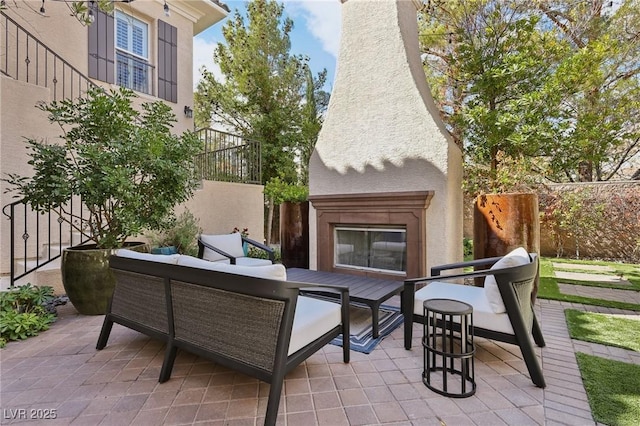 view of patio featuring fence and an outdoor living space with a fireplace