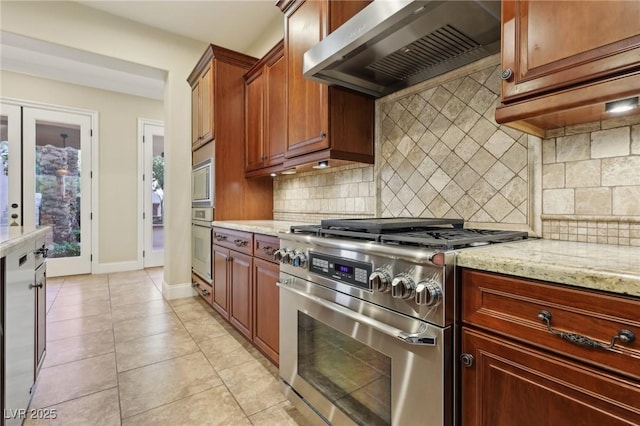 kitchen featuring stainless steel appliances, tasteful backsplash, light stone counters, and exhaust hood