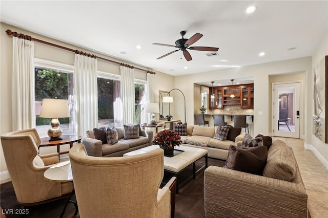 living area with a wealth of natural light, a ceiling fan, visible vents, and recessed lighting