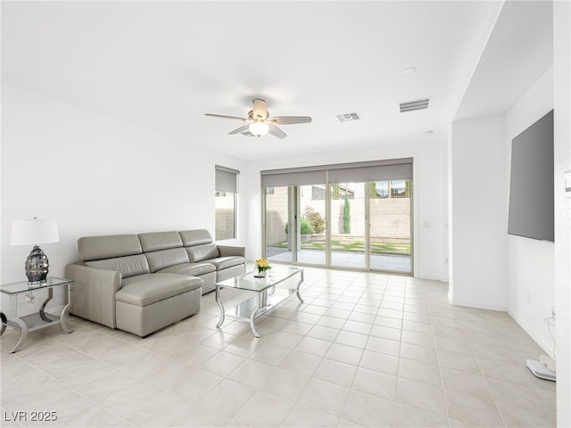 living room with a ceiling fan, visible vents, baseboards, and light tile patterned floors