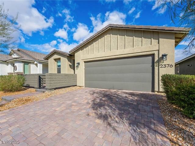 ranch-style home with decorative driveway, stucco siding, fence, a garage, and a tiled roof