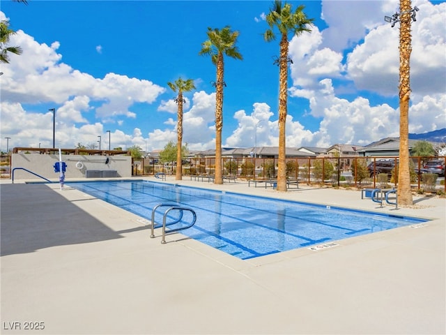 pool with a patio area and fence