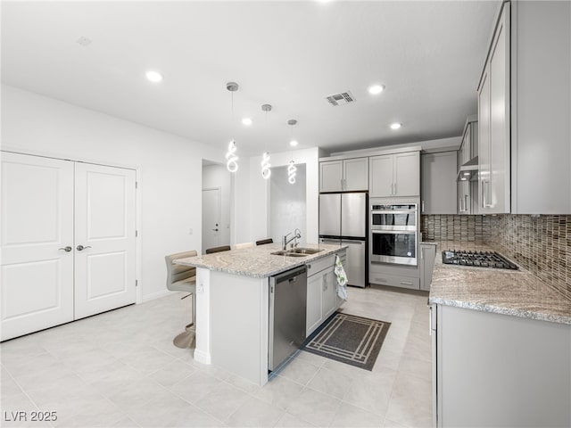 kitchen with stainless steel appliances, visible vents, decorative backsplash, gray cabinetry, and a sink