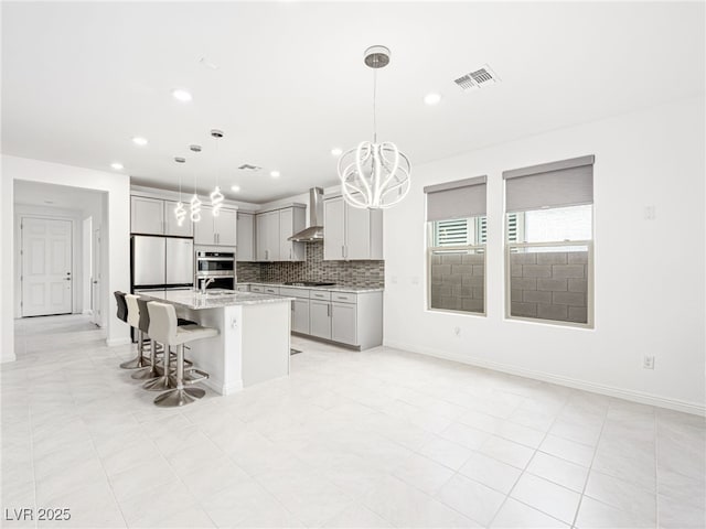 kitchen with visible vents, decorative backsplash, wall chimney exhaust hood, appliances with stainless steel finishes, and gray cabinets