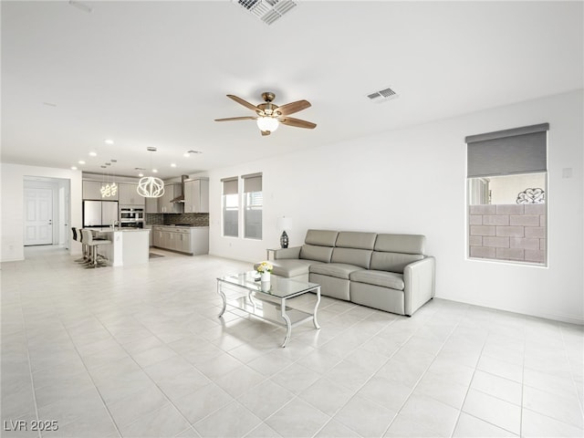 living room with a healthy amount of sunlight, visible vents, and a ceiling fan