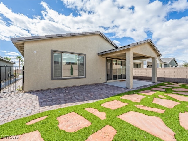 back of property with a patio, fence, and stucco siding