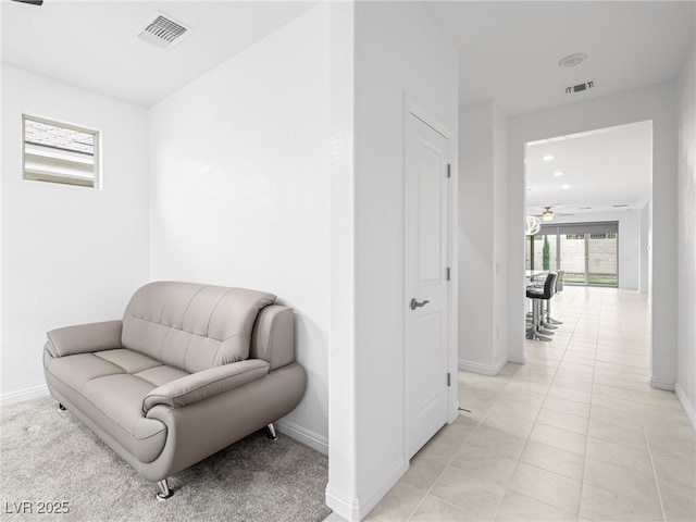 living area featuring light tile patterned floors, visible vents, and baseboards