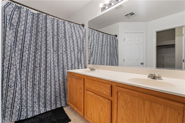 full bath with a sink, visible vents, double vanity, and tile patterned floors