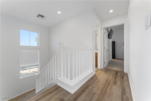 hallway featuring an upstairs landing, visible vents, a healthy amount of sunlight, and recessed lighting