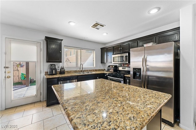 kitchen featuring light stone counters, visible vents, appliances with stainless steel finishes, and a sink